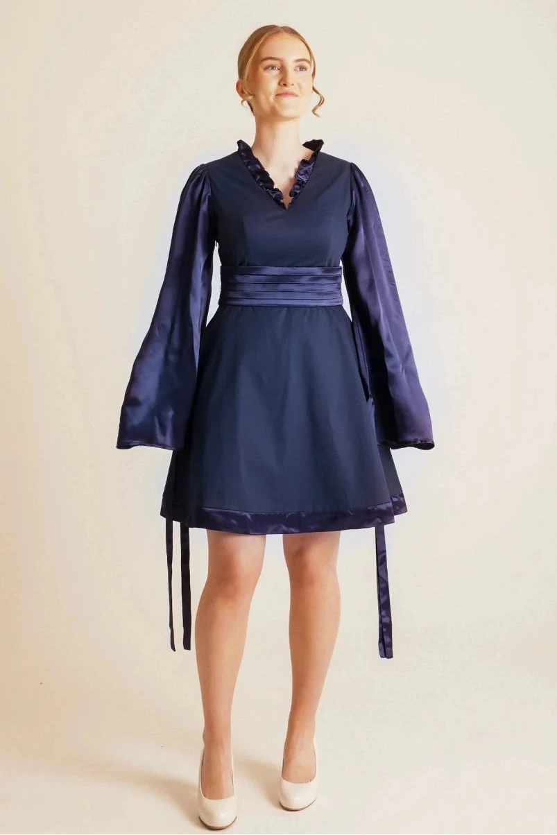 Woman wearing a navy blue dress with long sleeves on a beige background