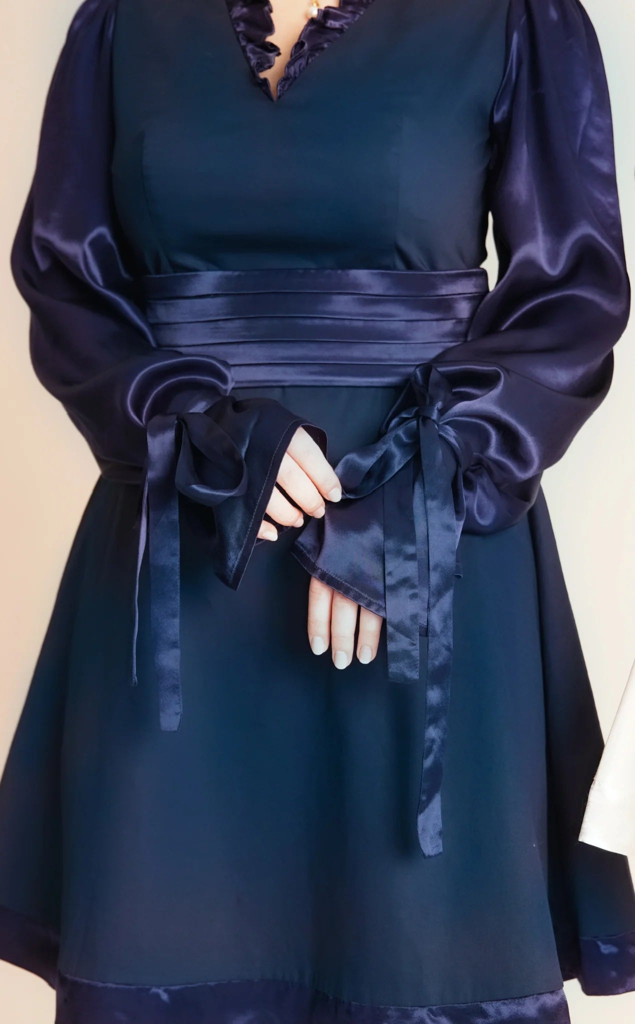 Navy blue dress with long sleeves and a belt on a beige background