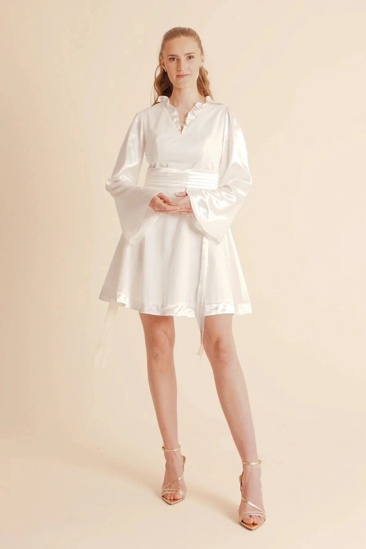 Woman wearing a white satin dress on a beige background