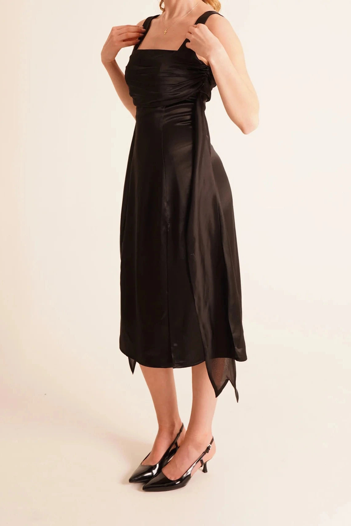 Woman wearing a black satin dress on a beige background